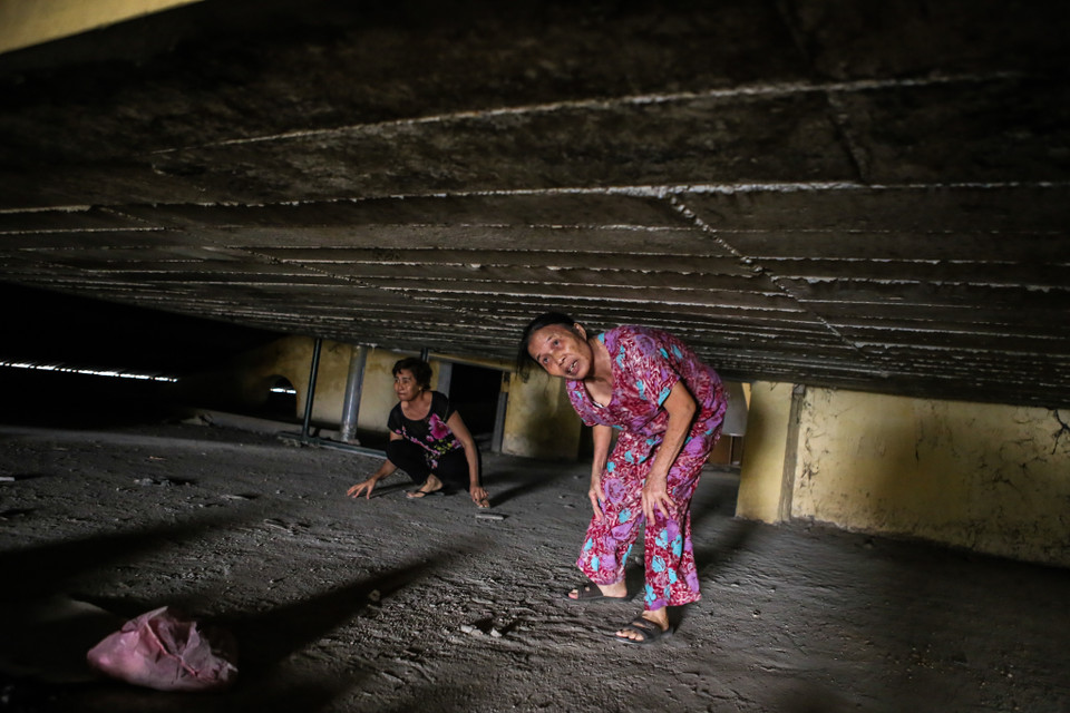 Bà Vũ Thị Xuân (70 tuổi) sống tại tầng 8 thuộc đơn nguyên I của tòa nhà này cho biết, bà bị huyết áp cao không thể leo bộ xuống tầng 1 nên hàng ngày mỗi khi đi chơ bà buộc phải leo lên tầng 11 rồi chui qua tòa nhà bên kia để đi thang máy. (Ảnh: Minh Sơn/Vietnam+)