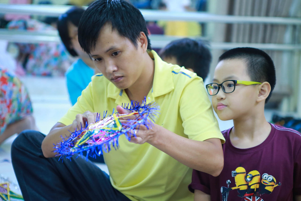 Hướng dẫn các cháu nhỏ làm đèn ông sao (Ảnh: Minh Sơn/Vietnam+)