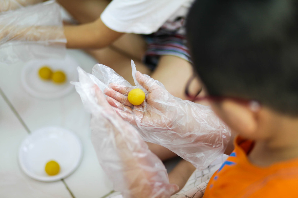 Dù vẫn còn vụng về nhưng các em học sinh tiểu học vẫn rất hào hứng tham gia lớp học làm bánh Trung thu do chính cô giáo và cha mẹ các em dạy. (Ảnh: Minh Sơn/Vietnam+)