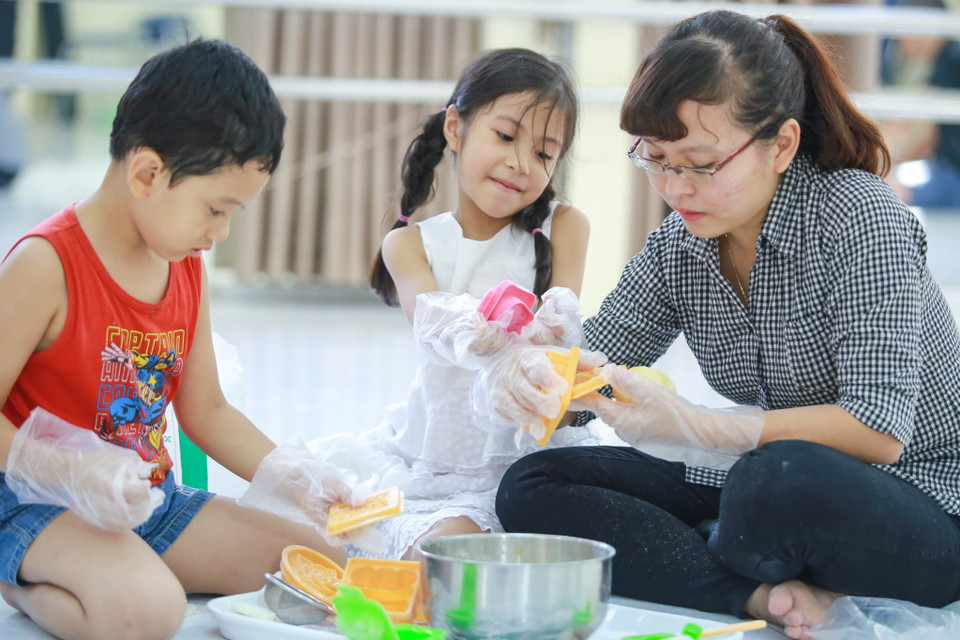 Công việc làm bánh tưởng chừng như rất đơn giản nhưng cũng khá khó khăn đối với các bé, nhiều phụ huynh cũng sẵn sàng giúp con em mình ‘hoàn thành nhiệm vụ’. (Ảnh: Minh Sơn/Vietnam+)