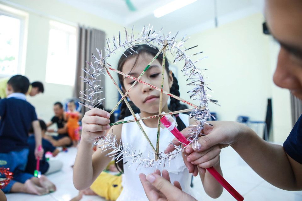 Ngoài làm bánh, các bé còn được phụ huynh dạy cho cách làm đèn ông sao, một đồ chơi không thể thiếu mỗi dịp Trung thu về. (Ảnh: Minh Sơn/Vietnam+)