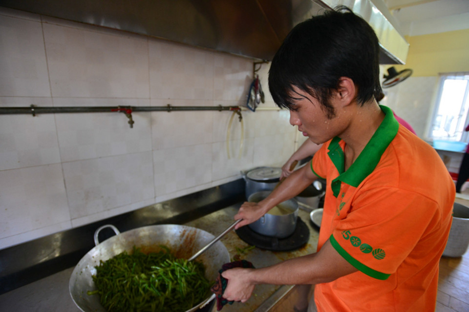 Một tình nguyện viên mướt hồ hôi khi bạn đã trực ở phòng bếp liên tục 3 tiếng đồng hồ để xào hết 75 cân rau. (Ảnh: Minh Sơn/Vietnam+)