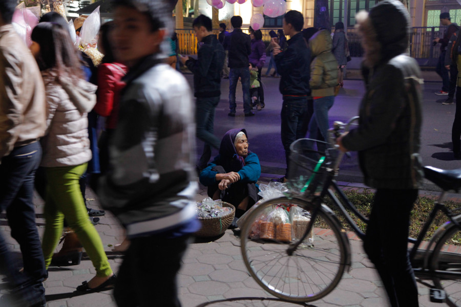 Bà cụ bán hàng rong giữa dòng người vui chơi ngày cuối năm. (Ảnh: Thành Nguyễn/Vietnam+)