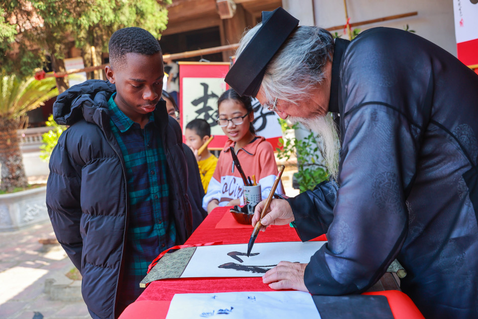 Oraiden Manuel, sinh viên Mozambique hiện đang học tại Bách Khoa đang trải nghiệm phong tục xin chữ tại đình làng Mông Phụ. (Ảnh: Minh Sơn/Vietnam+)