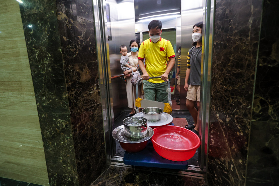 Họ phải chờ xếp hàng lấy nước, đợi thang máy, chở về căn hộ... mất rất nhiều thời gian. (Ảnh: Minh Sơn/Vietnam+)