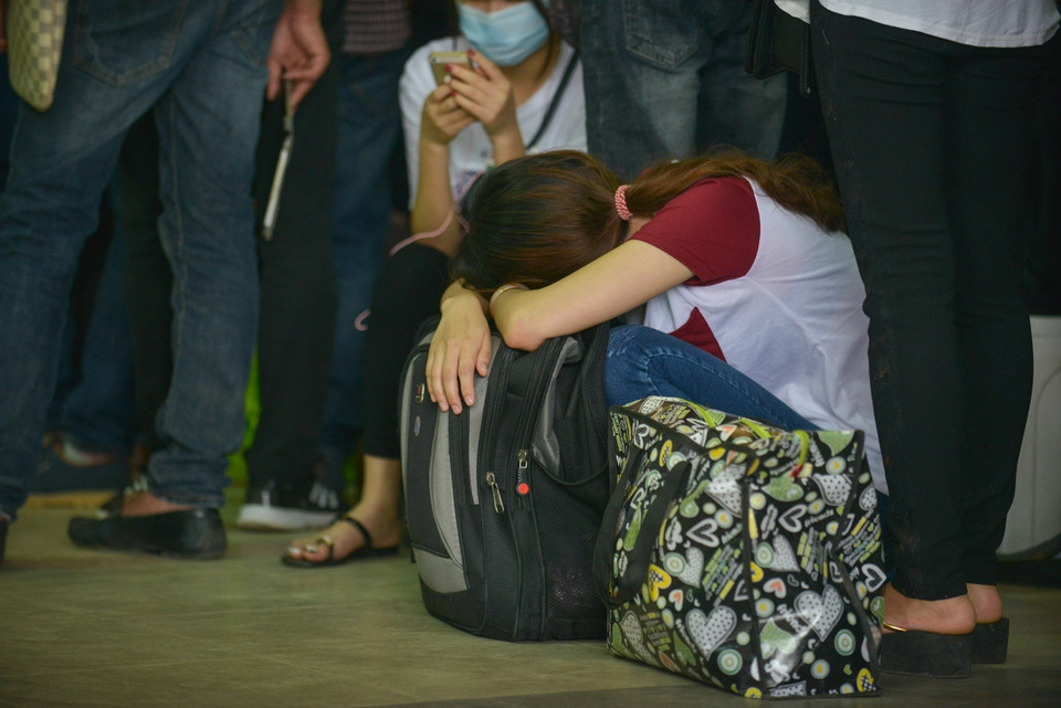 Một cô gái ngủ gục vì chờ đợi xếp hàng mua vé quá lâu. (Ảnh: Minh Sơn/Vietnam+)