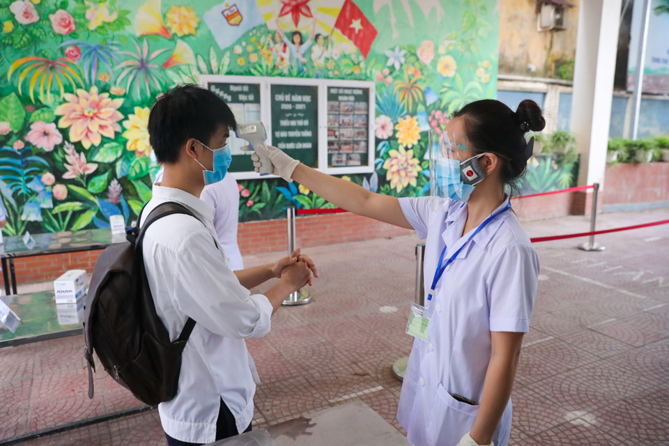 Các thí sinh được đo thân nhiệt, sát khuẩn tay trước khi vào phòng thi. (Ảnh: Minh Sơn/Vietnam+)