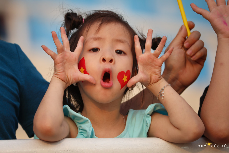 Một bé gái với hình ảnh cờ Việt Nam dán trên má đi cổ vũ các vận động viên điền kinh ở sân vận động Mỹ Đình. (Ảnh: Vietnam+)
