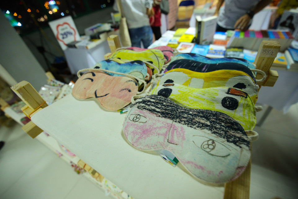 Gian hàng bán những sản phẩm thời trang được in từ tranh vẽ của các em nhỏ tự kỉ. (Ảnh: Minh Sơn/Vietnam+)