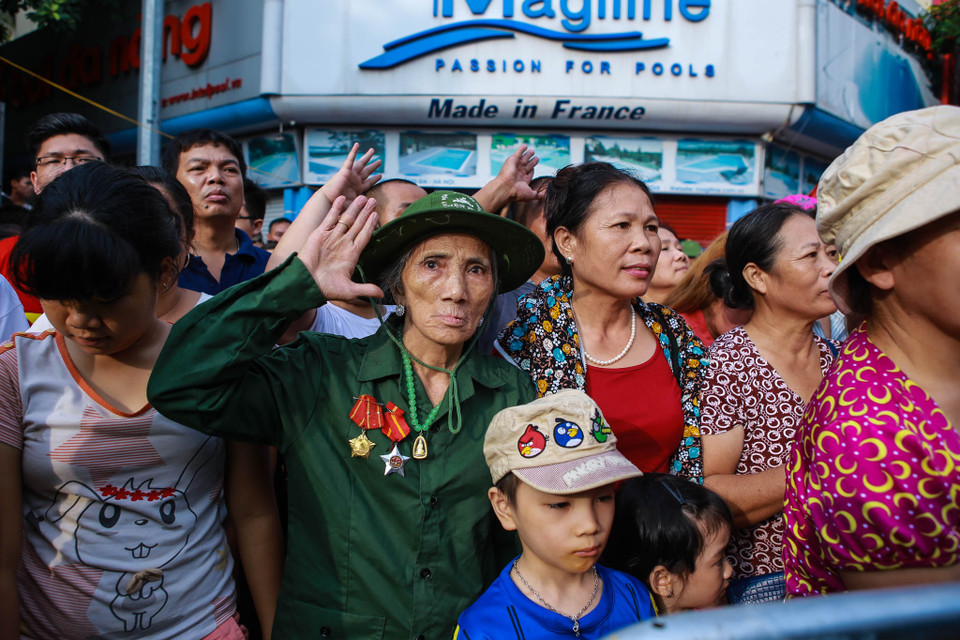 Khi tiếng nhạc Quốc ca cất lên, vẫn giữ tác phong của một quân nhân, cụ giơ tay lên chào cờ. (Ảnh: Minh Sơn/Vietnam+)