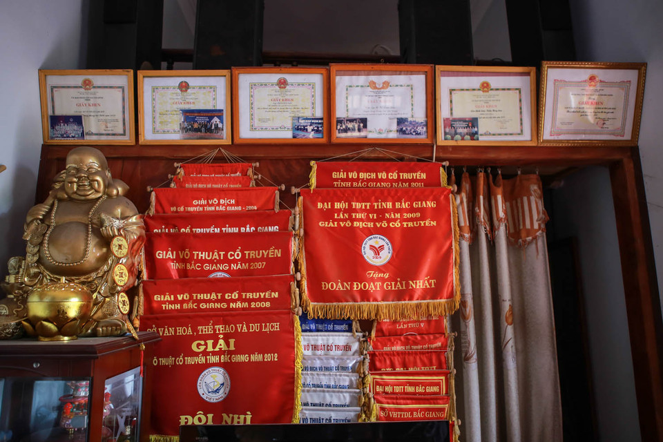 Căn nhà nhỏ treo đầy những kỷ niệm chương, huân chương mà các học trò của ông giành được. Ông khoe từ lúc thành lập câu lạc bộ, các học trò của ông đã đem về cho huyện hơn 100 tấm huy chương các loại. (Ảnh: Minh Sơn/Vietnam+)