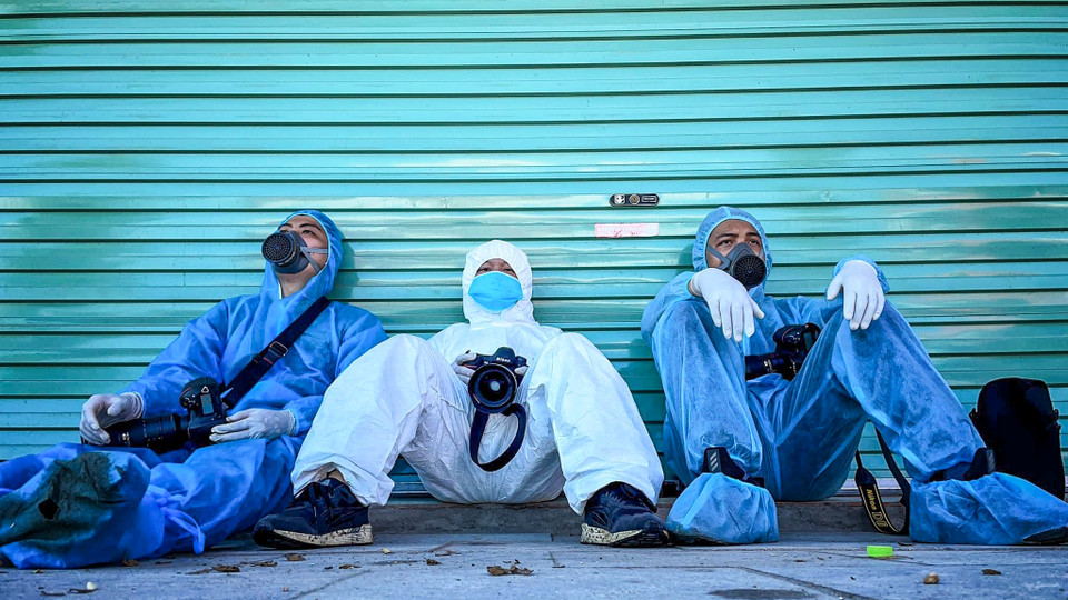 Phút nghỉ ngơi hiếm hoi của các phóng viên ảnh. Nhiều phóng viên cho biết, họ đã phải mặc bộ đồ bảo hộ y tế đứng hàng tiếng giữa trời nắng nóng để tác nghiệp. (Ảnh: Giang Huy)