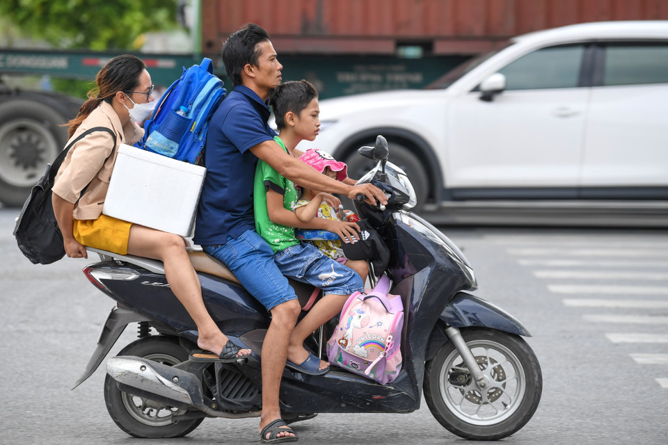Cảnh cả gia đình mang theo nhiều đồ đạc đèo nhau trên xe máy không phải cảnh hiếm gặp. (Ảnh: Minh Sơn/Vietnam+)
