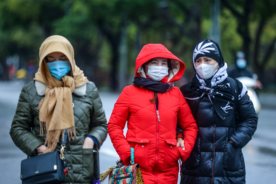 Nhiều người dân Thủ đô co ro trong giá lạnh, có người phải mặc áo mưa khi đi đường. (Ảnh: Minh Sơn/Vietnam+)