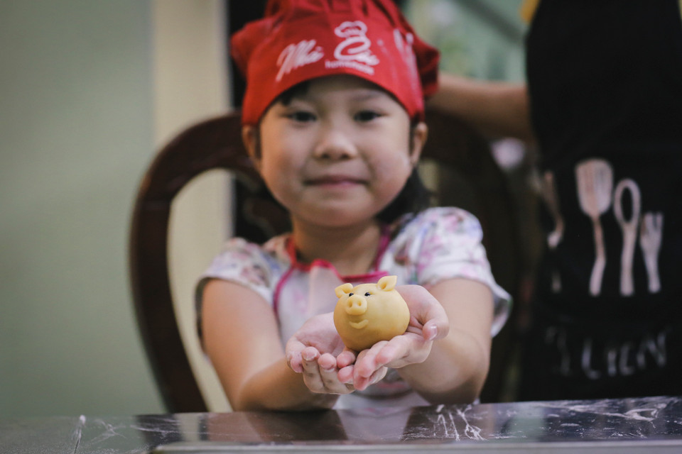 Bé Diệp Anh (6 tuổi) khoe chiếc bánh nướng hình con heo xinh xắn vừa làm xong. Bé Diệp Anh cho biết sẽ mang bánh về tặng em mình. (Ảnh: Minh Sơn/Vietnam+)