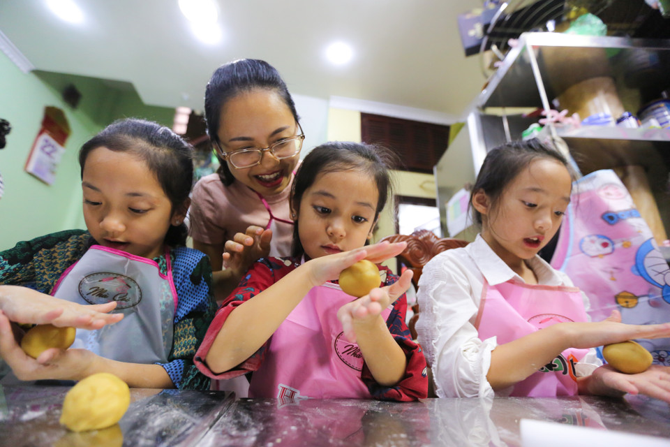 Chị Lã Thu Giang, chủ hiệu bánh Nhà còi đang hướng dẫn các học viên nhí làm ra những chiếc bánh nướng đầu tiên trong đời. Chị Giang cho biết: 'Hồi bé, cả một mùa Trung thu mình ấn tượng nhất là những thứ bánh cá, bánh con lợn nên mình tìm tòi làm những bánh Trung thu hình con giống... (Ảnh: Minh Sơn/Vietnam+)