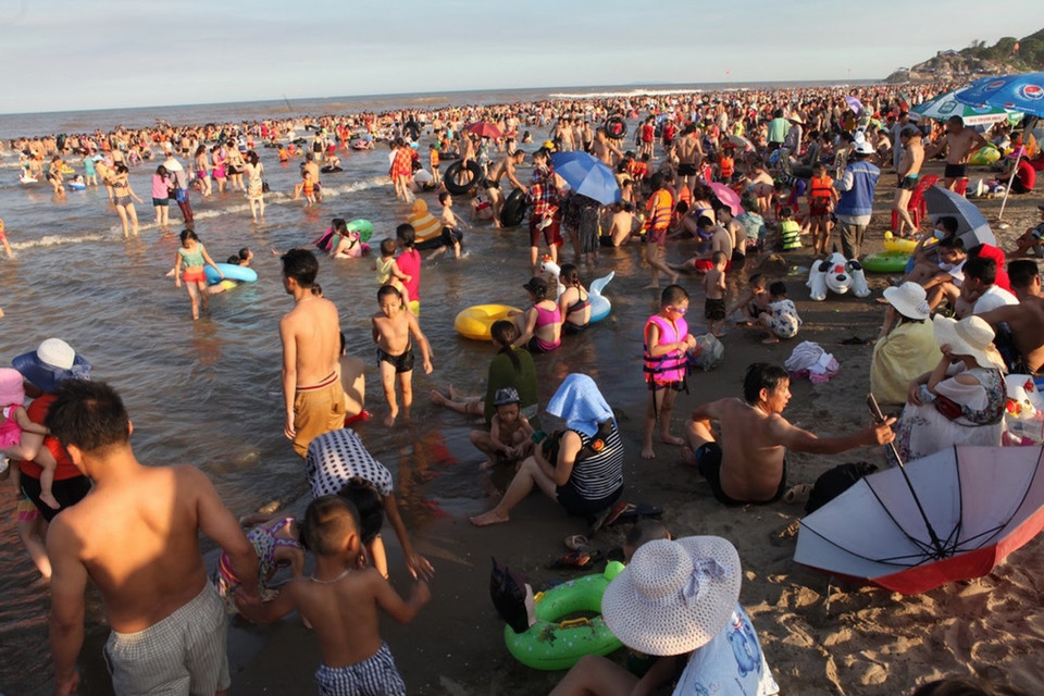 Nhiều gia đình đã phải ngồi trên bờ để chờ… đến lượt bơi vì quá đông. (Ảnh: PV/Vietnam+)