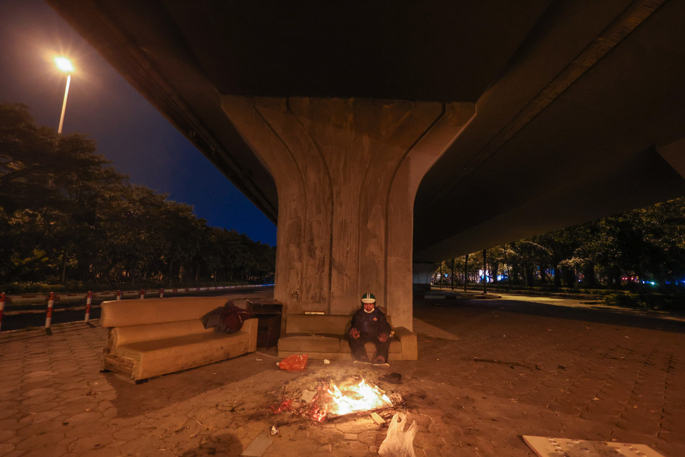 Có những đêm nhiệt độ Hà Nội giảm sâu, anh phải đốt lửa trên vỉa hè để sưởi ấm. (Ảnh: Minh Sơn/Vietnam+)