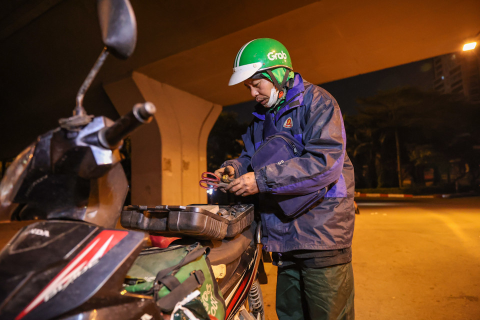 Anh Ngô Đăng Nam đến từ Thái Bình làm công việc cứu hộ xe ban đêm. Anh bắt đầu công việc từ 6 giờ tối đến 6 giờ sáng. Mặc dù biết thời tiết này sẽ không có nhiều khách nhưng anh vẫn phải cố gắng làm việc để kiếm thêm tiền tiêu Tết. (Ảnh: Minh Sơn/Vietnam+)