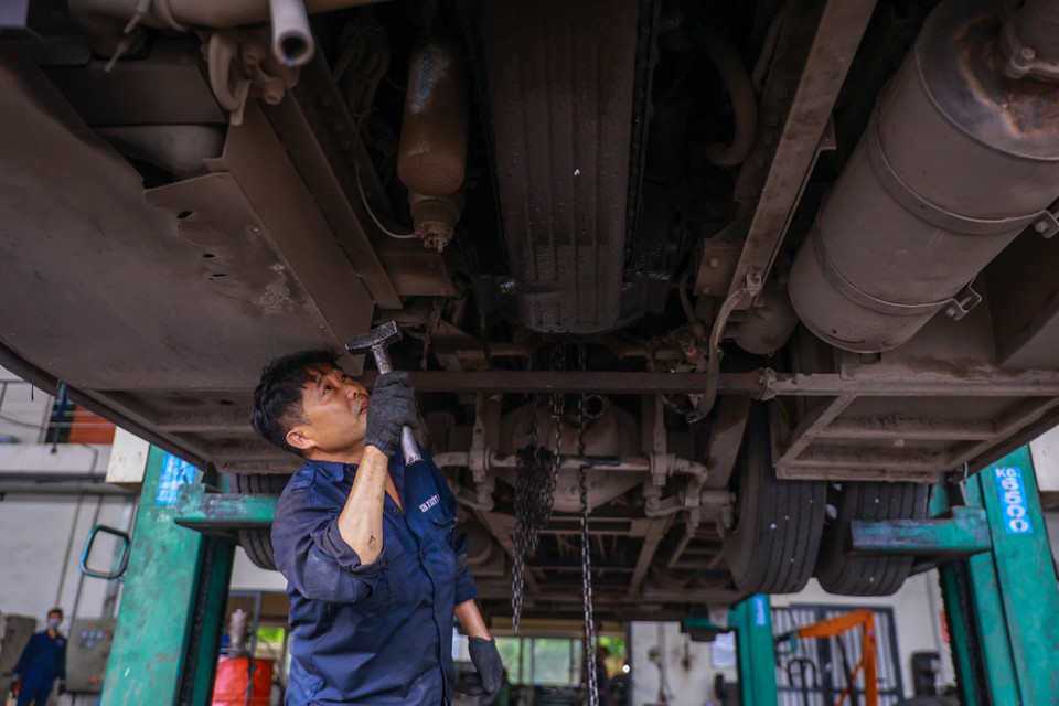 Anh Nguyễn Mạnh Tân, một thợ bảo dưỡng máy gầm đã có gần 20 năm gắn bó với nghề sửa chữa, bảo dưỡng xe buýt đang dùng búa gõ các phần của gầm xe. (Ảnh: Minh Sơn/Vietnam+)