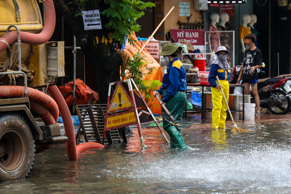 Lực lượng chức năng túc trực và cắm biển báo khu vực ngập nặng. (Ảnh: Minh Hiếu/Vietnam+)