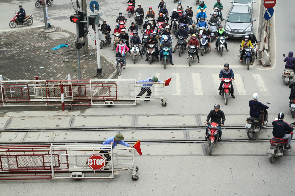 Trên đường Giải Phóng, mặc dù có rào chắn cẩn thận nhưng khi tàu chuẩn bị chạy qua, nhiều người dân vẫn bất chấp tính mạng vượt qua. (Ảnh: Minh Sơn/Vietnam+)