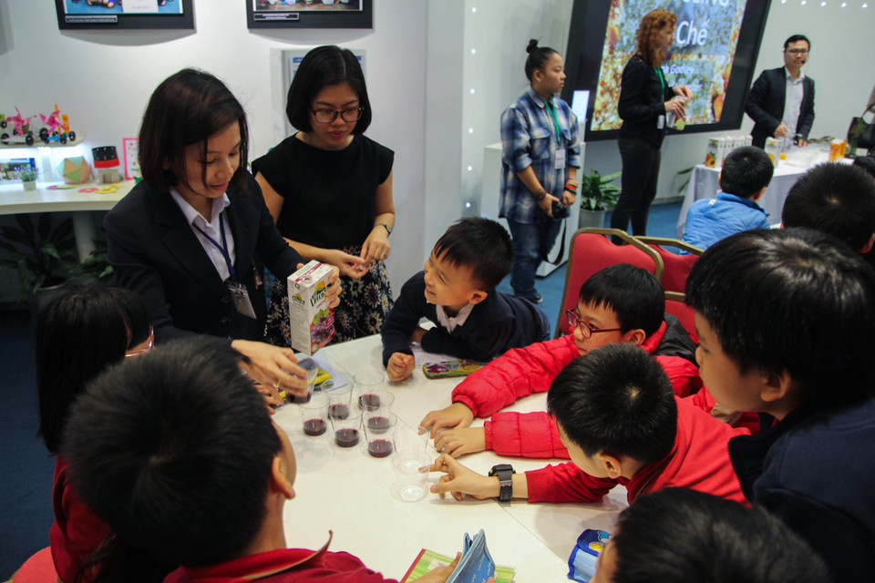 Các em nhỏ thích thú với các thí nghiệm tạo ‘dung dịch đổi màu liên tục’ từ đá khô do tiến sĩ Từ Minh Hiệu thực hiện. (Ảnh: Minh Sơn/Vietnam+) 