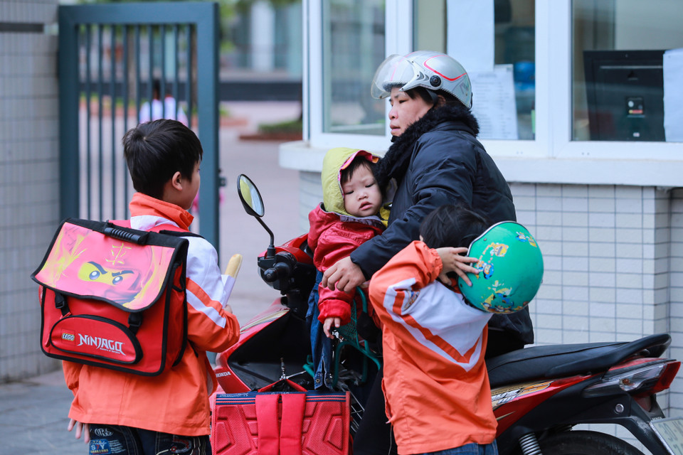 Không chỉ học sinh mà phụ huynh cũng gặp rất nhiều khó khăn khi không khí lạnh đột ngột bao phủ khắp Thủ đô. (Ảnh: Minh Sơn/Vietnam+)