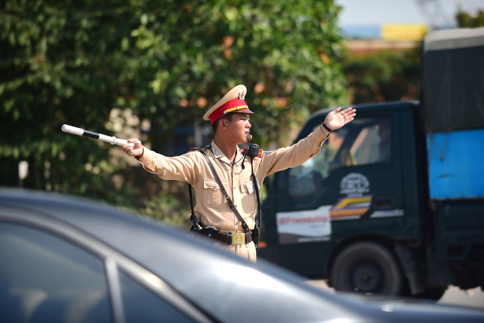 Không một phút nghỉ ngơi, các chiến sỹ CSGT chốt tại chân cầu Vĩnh Tuy luôn luôn trong trạng thái trực chiến, phân luồng để đảm bảo giao thông được thông suốt. (Ảnh: Minh Sơn/Vietnam+)