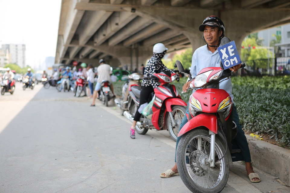 Một người xe ôm tại bến xe Mỹ Đình đã phải đi lại liên tục quanh khu vực để bắt khách. ‘Trời nắng như thế này nếu đứng một chỗ thì không có khách cháu ạ. Không đi làm thì lấy gì mà ăn’. (Ảnh: Minh Sơn/Vietnam+)