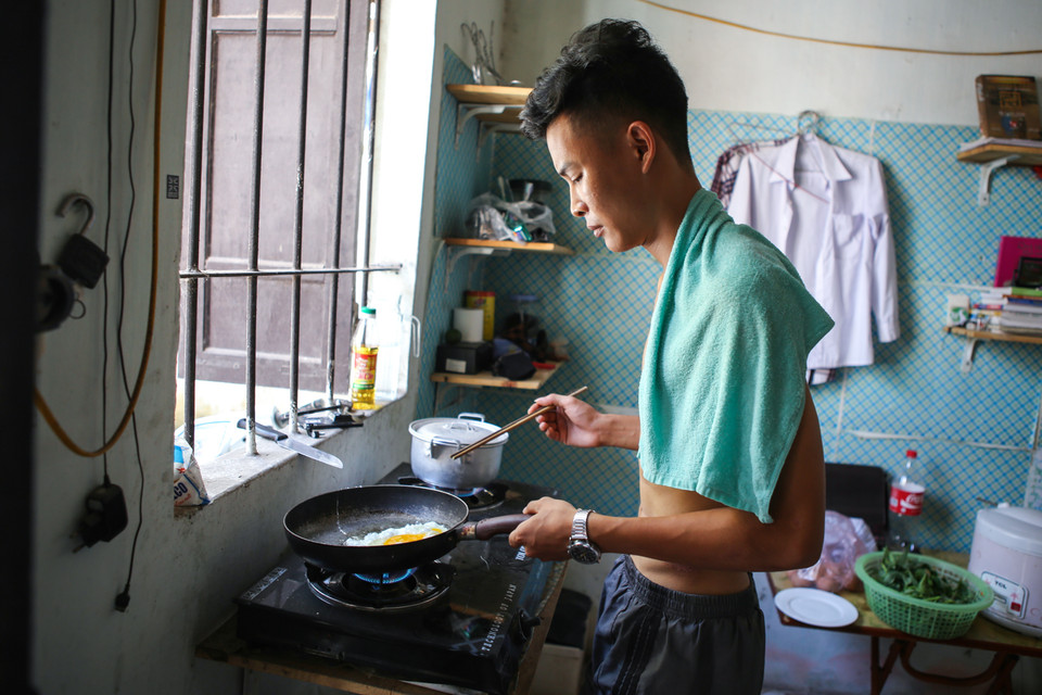 Để đỡ nóng, Hoàng luôn cởi trần và vắt trên mình một chiếc khăn ướt để chống nóng. (Ảnh: Minh Sơn/Vietnam+)