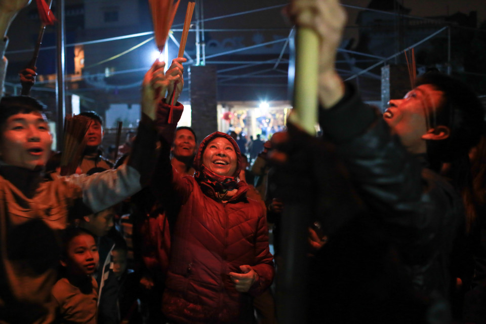 Dân làng An Định ở bên ngoài đã cầm sẵn những thẻ hương để lấy lộc. (Ảnh: Minh Sơn/Vietnam+)