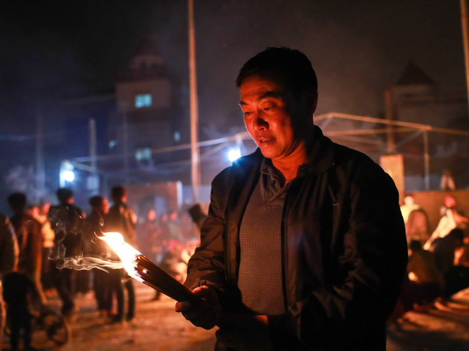 Nhiều người không vội vã, đợi người trong làng mang hết lửa đi mới ra xin lửa về nhà thắp hương. (Ảnh: Minh Sơn/Vietnam+)