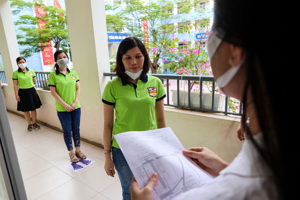 Trước khi vào phòng thi, thí sinh phải gỡ khẩu trang để cán bộ coi thi kiểm tra, sau đó đeo khẩu trang vào phòng thi và trong suốt thời gian làm bài thi. (Ảnh: Minh Sơn/Vietnam+)