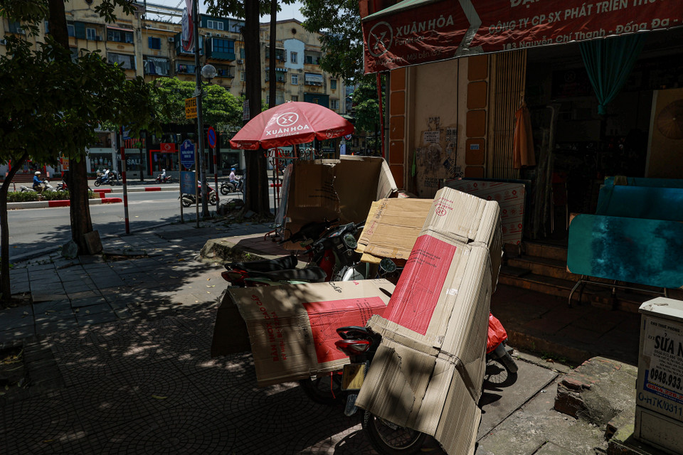 Nhiều cửa hàng phải dùng bìa các tông để phủ lên yên xe. (Ảnh: PV/Vietnam+)