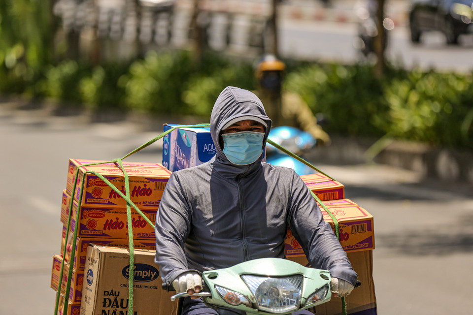 Những người bắt buộc phải di chuyển trên đường đều khoác lên mình các trang phục, phụ kiện chống nắng kín mít. (Ảnh: PV/Vietnam+)