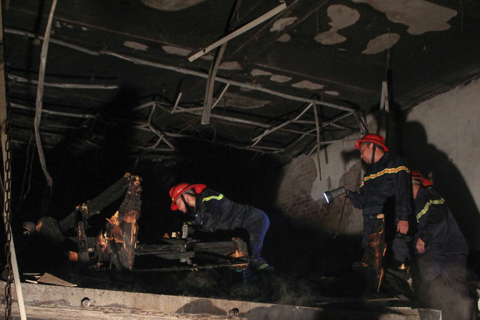 Rà soát lại đống hoang tàn của ngôi nhà. (Ảnh: Minh Sơn/Vietnam+)