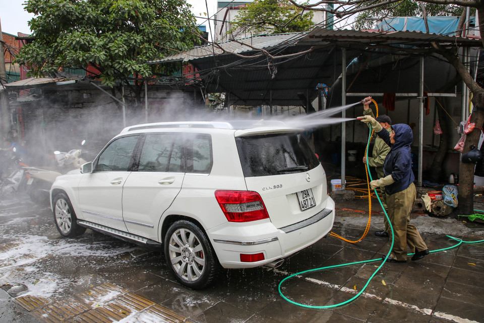 Chủ một cửa hàng rửa xe trên đường Nguyễn Khánh Toàn cho biết, dịp cận Tết nên các khách hàng có nhu cầu rửa xe phải chờ đợi rất lâu, có người phải chờ hàng tiếng đồng hồ mới tới lượt. (Ảnh: Minh Sơn/Vietnam+)