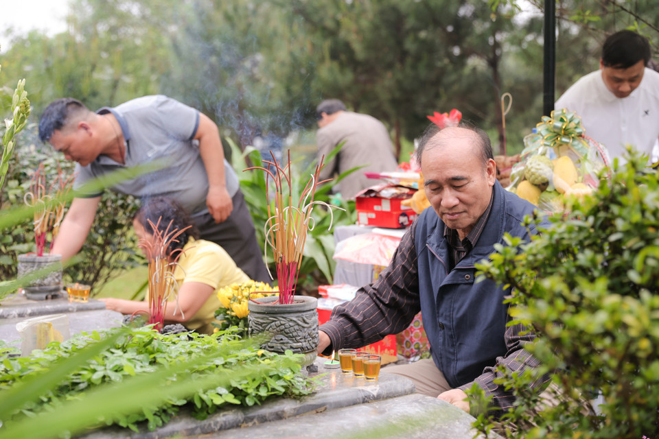 Mọi người mang theo khăn, chổi ra phần mộ để lau dọn lại, giúp nơi yên nghỉ của người đã khuất thêm khang trang, sạch đẹp. (Ảnh: Quỳnh Anh/Vietnam+)