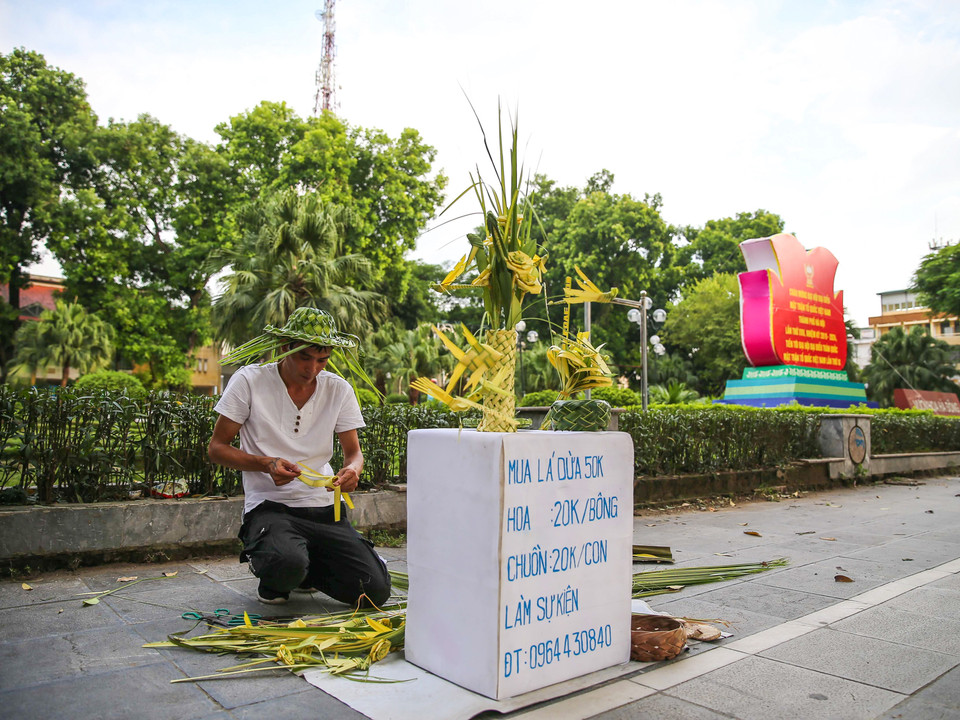 Cứ chiều chiều bên cạnh vườn hoa Hà Đông (Hà Nội), nhiều người dân Thủ đô lại tò mò thấy một người đàn ông đang tỉ mẩn tỉa tót từng chiếc lá dừa thành hình dáng chú chuồn chuồn, cánh bướm hay chú cào cào. (Ảnh: Vietnam+)