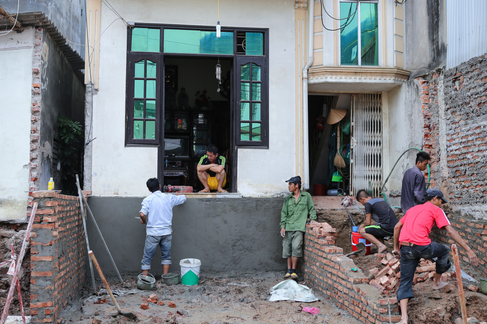 Sau hơn 4 tháng đưa vào sử dụng, hệ thống vỉa hè, đường ống thoát nước vẫn đang tiếp tục thi công bừa bộn. Một số đoạn vỉa hè hoàn thiện, nhưng rất thấp so với nền của những ngôi nhà. (Ảnh: Minh Sơn/Vietnam+)