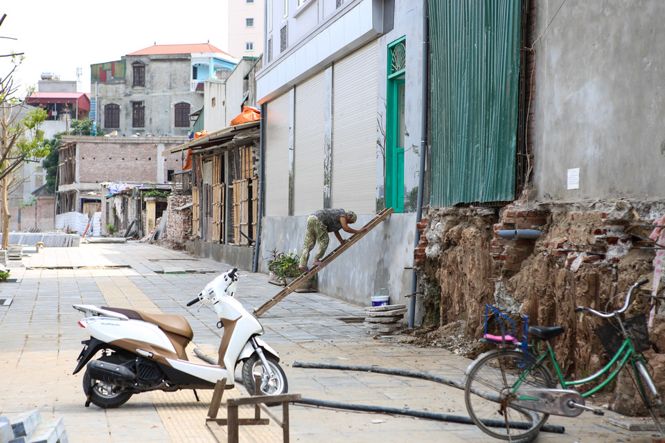 Nhiều người dân ở ngoài mặt đường phải bắc thang để vào nhà, còn người dân trong ngõ phải dựng tạm cầu gỗ để đi vào. (Ảnh: Minh Sơn/Vietnam+)