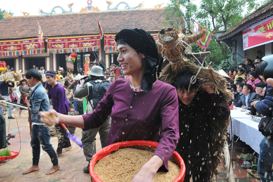 Nam đóng giả nữ, nữ đóng giả nam đem những mủng trấu tung khắp xuống đồng theo nhịp chiêng trống. (Ảnh: PV/Vietnam+)