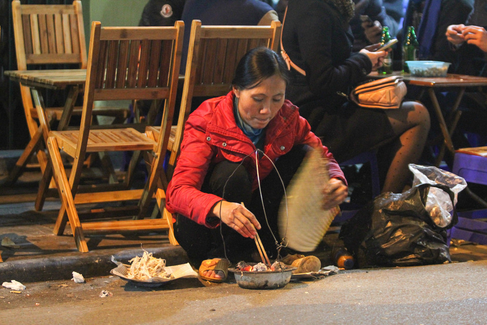 Một cô bán mực rong nhanh tay quạt để kịp phục vụ thực khách. (Ảnh: Minh Sơn/Vietnam+)