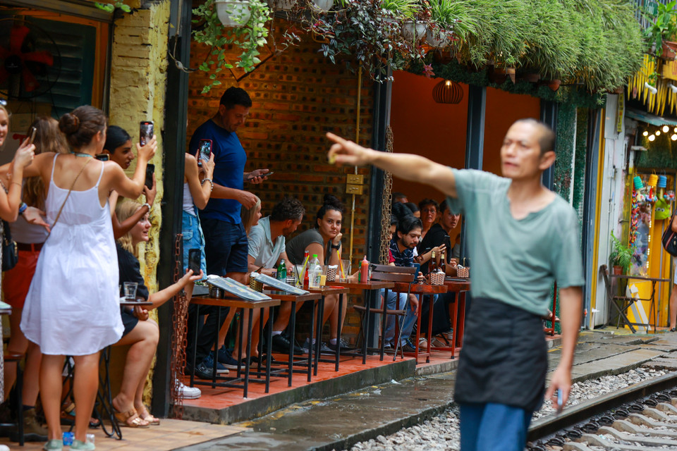 Khi tàu chuẩn bị tới, nhân viên các quán hàng quán tự báo động để khách chú ý đứng gọn ra khỏi đường ray đảm bảo an toàn. (Ảnh: Minh Sơn/Vietnam+)