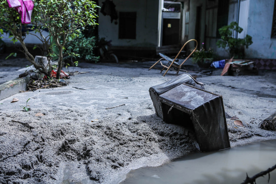 Phía trong con đường khu dân cư, bùn lầy và rác ngập ngụa. Những ngôi nhà vắng hoe, bùn lầy ngập sâu, đồ đạc hư hại ngổn ngang. (Ảnh: PV/Vietnam+)