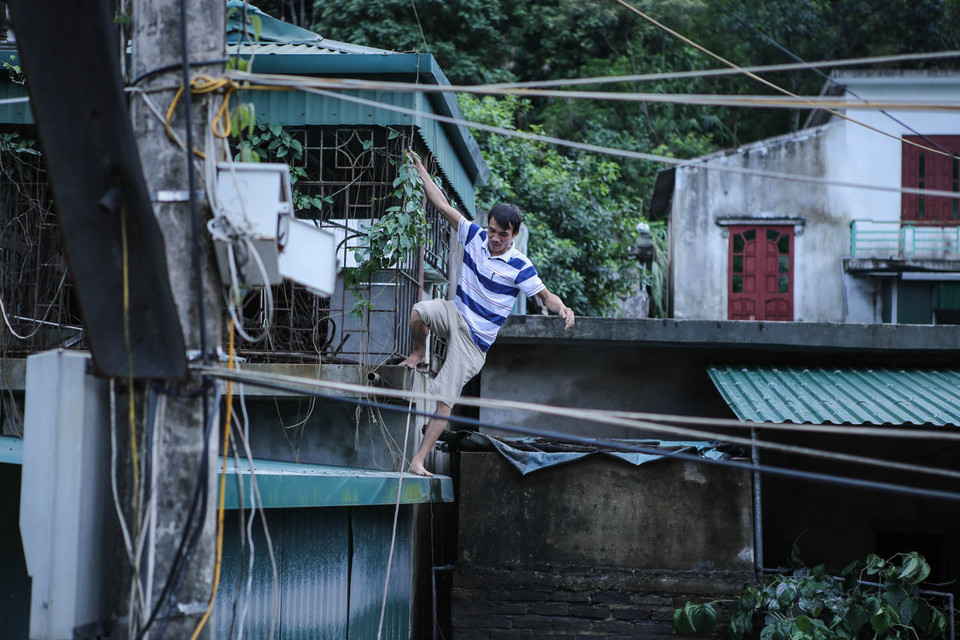 Rất nhiều người dân tại khu 4, phường Mông Dương cố gắng trở lại nhà của mình để vớt vát chút tài sản còn lại. Lũ bùn vẫn còn chưa rút nên họ buộc phải trèo qua các căn nhà. (Ảnh: PV/Vietnam+)