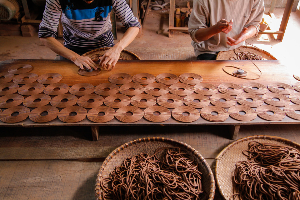  Những đôi tay thoăn thoắt của hai người thợ xoay trần làm hương vòng. Năng suất một ngày của hai người có thể lên đến hàng nghìn sản phẩm.(Ảnh: Thành Nguyễn/Vietnam+)