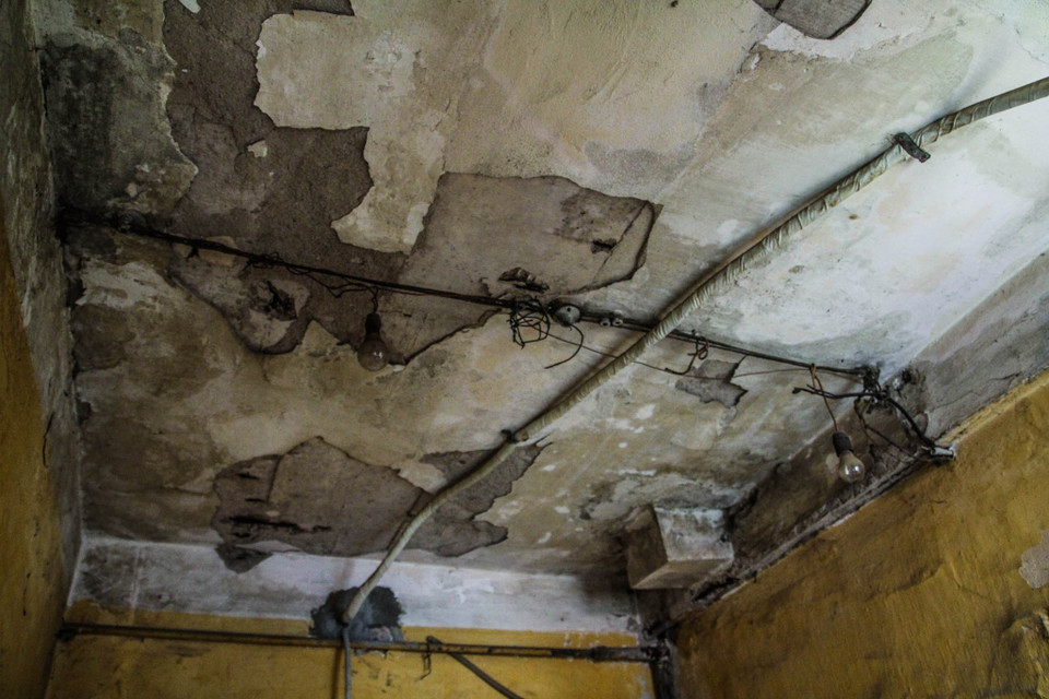 Trần nhà ngấm nước từ nhà vệ sinh bên trên xuống khiến nhiều người phải vừa đi vệ sinh vừa… đội nón. (Ảnh: Minh Sơn/Vietnam+)