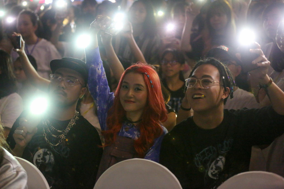 Mọi người cùng nhau bật đèn flash điện thoại để thắp sáng cho cả một chương trình. (Ảnh: Quang Sỹ/Vietnam+)